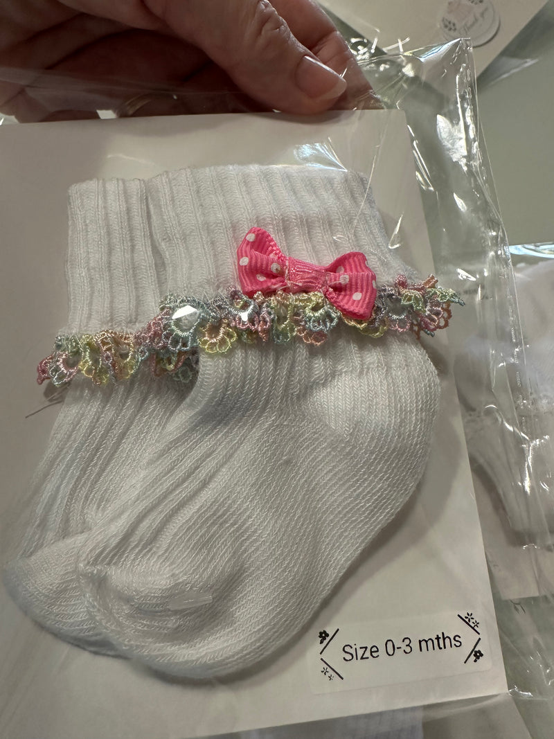 White baby cotton socks with pale rainbow lace trim and bow.