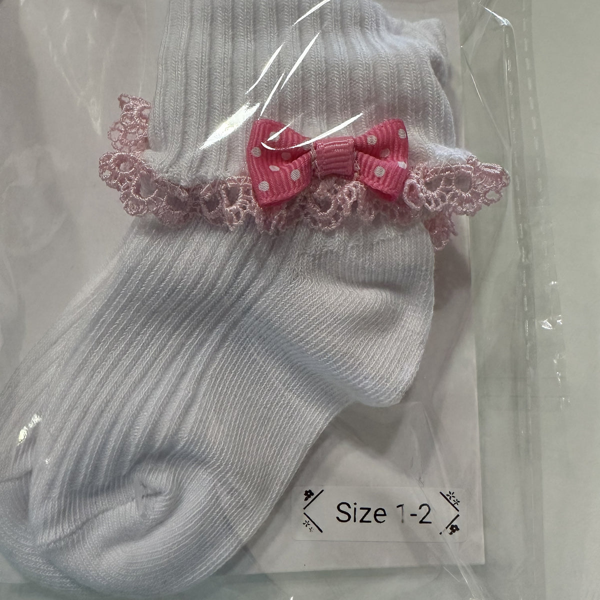 White baby cotton socks with pastel pink lace trim and pink bow.