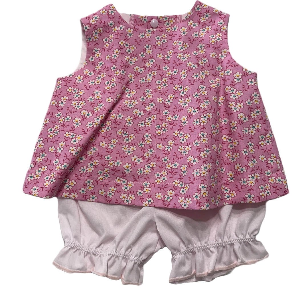 Baby outfit with pink floral top and white bloomers on a white background