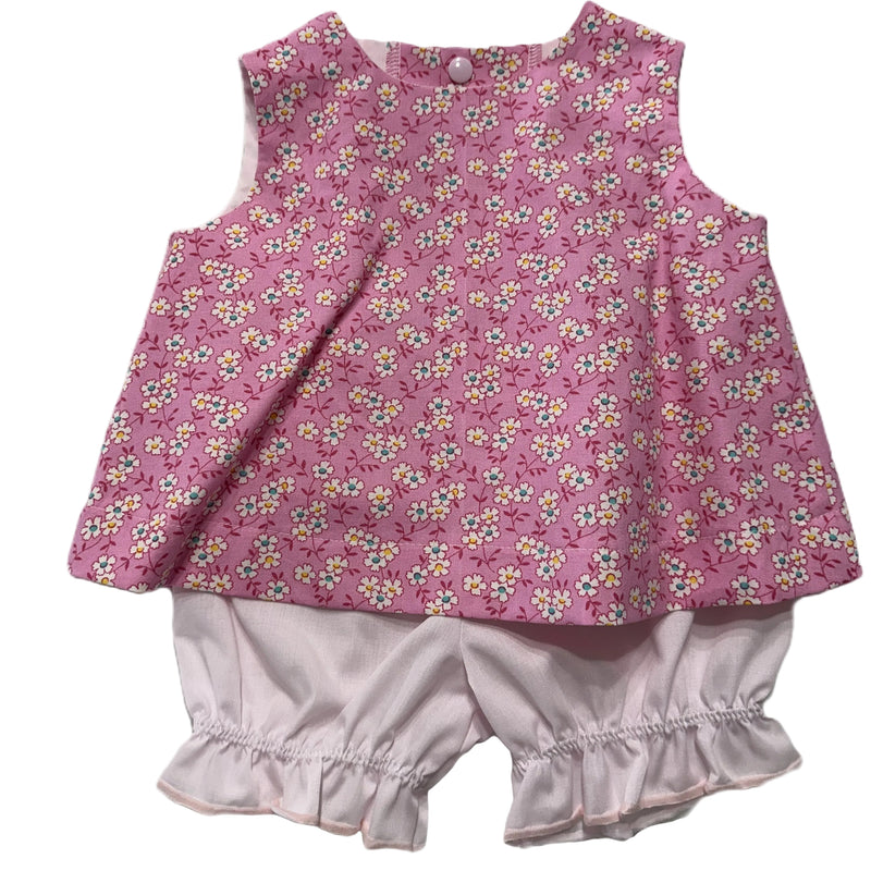 Baby outfit with pink floral top and white bloomers on a white background